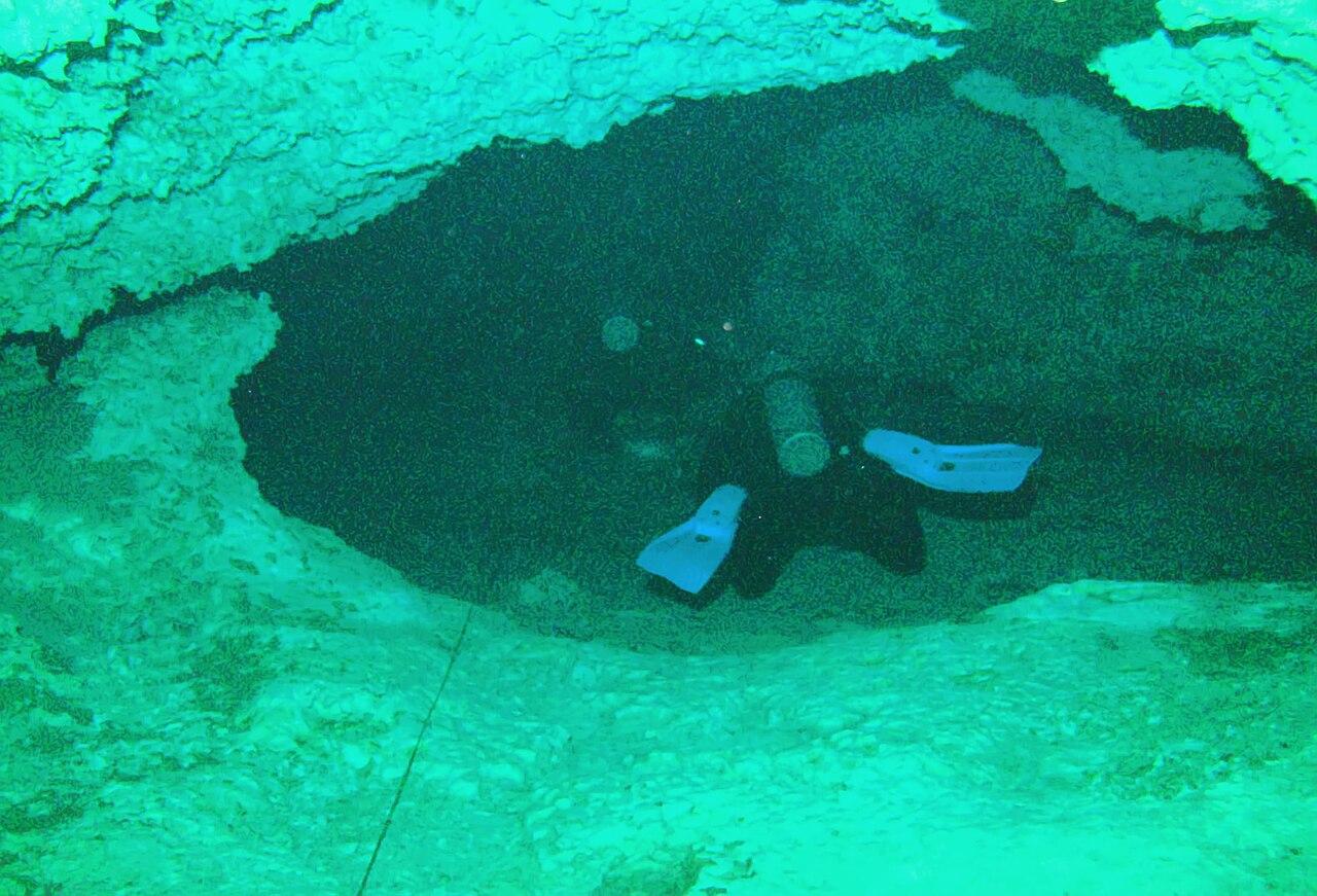 A scuba diver passes through a rock swim-through inside the Dos Ojos cenote system near Tulum, Mexico