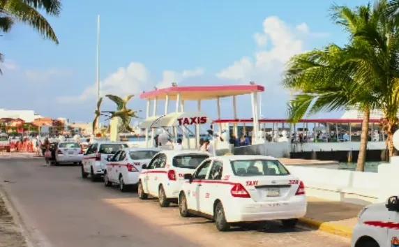 Row of Cozumel taxis queued at the covered waterfront taxi stand beside the palms